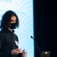 Scholar wearing mask and giving an oral presentation.